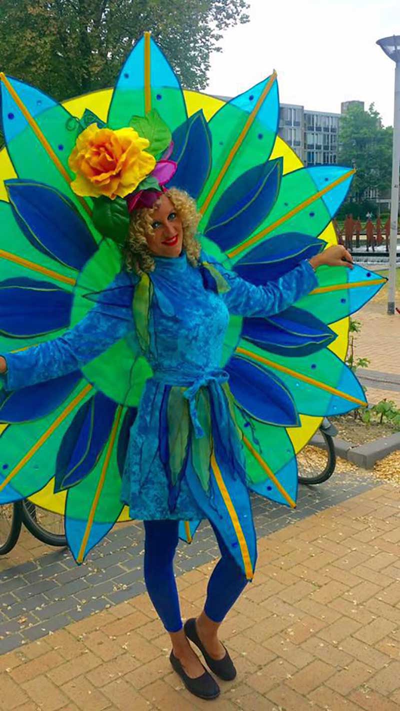 Een kleurrijke ontvangstact in een groot blauw en groen bloemenkostuum