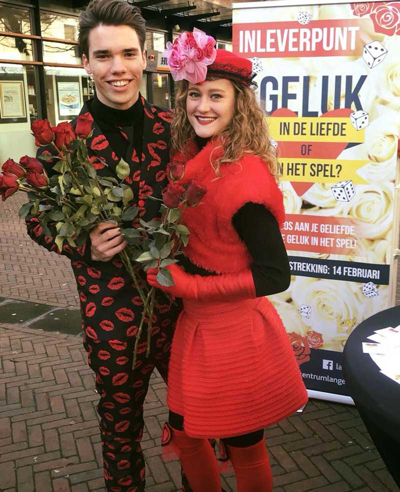Een promotieduo deelt rode rozen uit