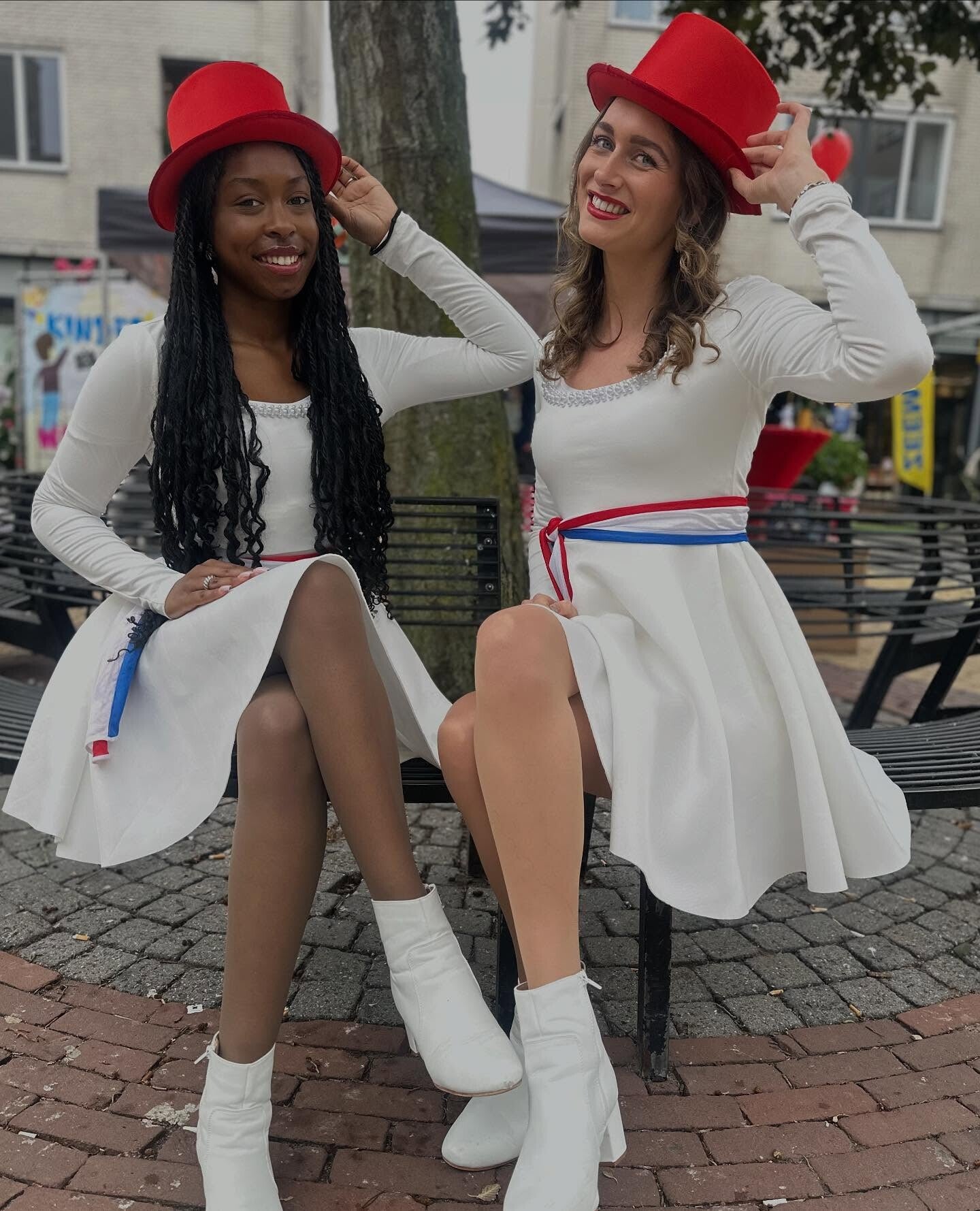 Twee ontvangstmedewerkers in witte outfits met rode hoge hoeden